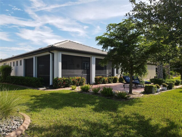 back of house with a sunroom, a lawn, and a patio area