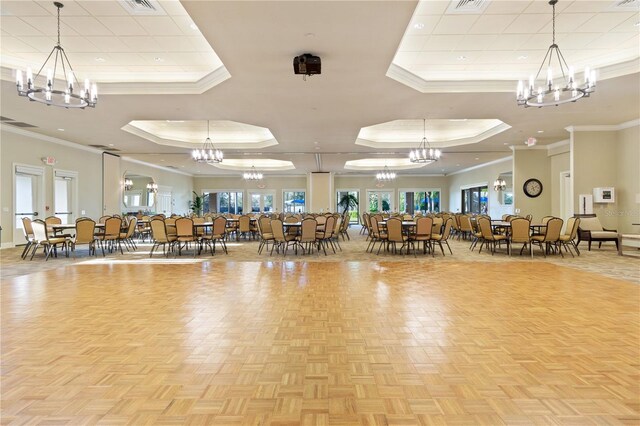 gym with crown molding, a raised ceiling, a chandelier, and light parquet floors