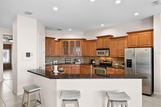 kitchen with tasteful backsplash, stainless steel appliances, a kitchen island, a breakfast bar area, and light tile patterned flooring