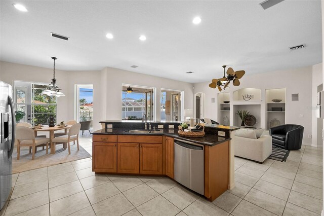 kitchen featuring dark stone countertops, sink, an island with sink, pendant lighting, and stainless steel dishwasher