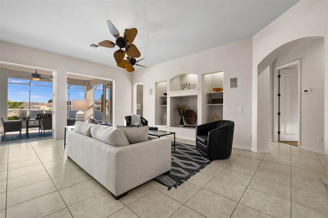 tiled living room featuring built in features and ceiling fan