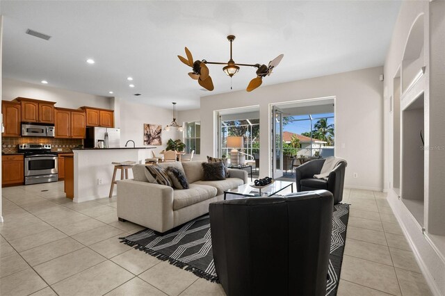 tiled living room with ceiling fan with notable chandelier