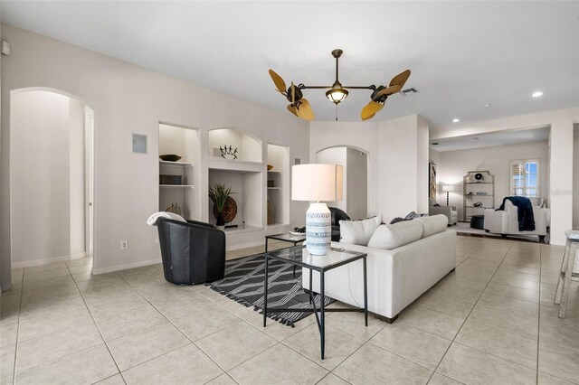 tiled living room featuring built in shelves and ceiling fan