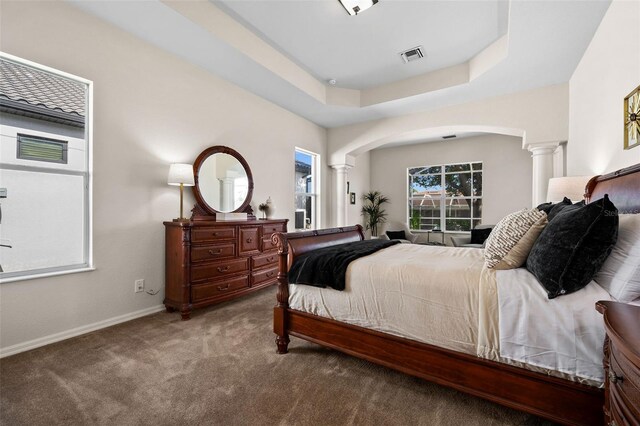 bedroom featuring a raised ceiling, carpet, and ornate columns