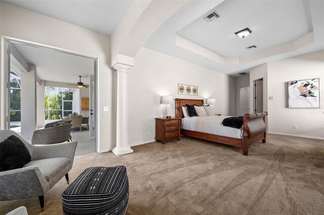 carpeted bedroom with a tray ceiling and decorative columns