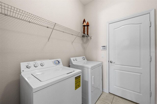 laundry room with washing machine and dryer and light tile patterned floors