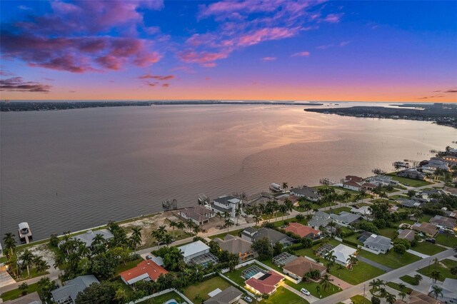 aerial view at dusk featuring a water view