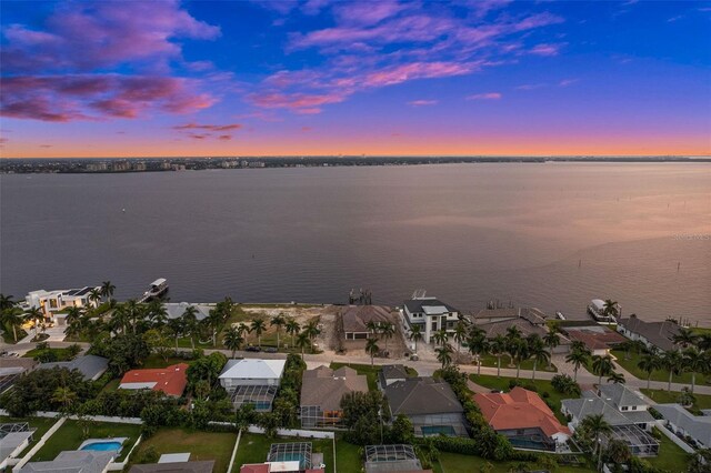 aerial view at dusk featuring a water view