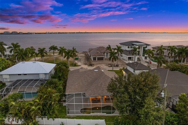 aerial view at dusk featuring a water view