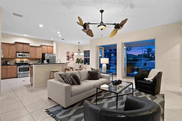 living room with light tile patterned floors and ceiling fan with notable chandelier