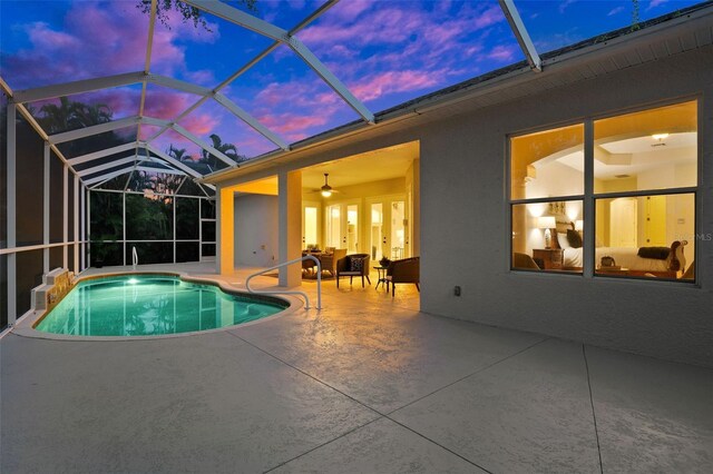 pool at dusk with ceiling fan, a lanai, and a patio