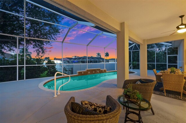 pool at dusk featuring glass enclosure and a patio