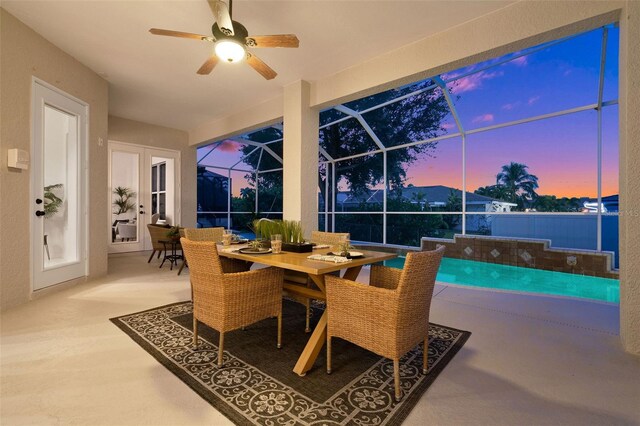 patio terrace at dusk featuring ceiling fan and glass enclosure