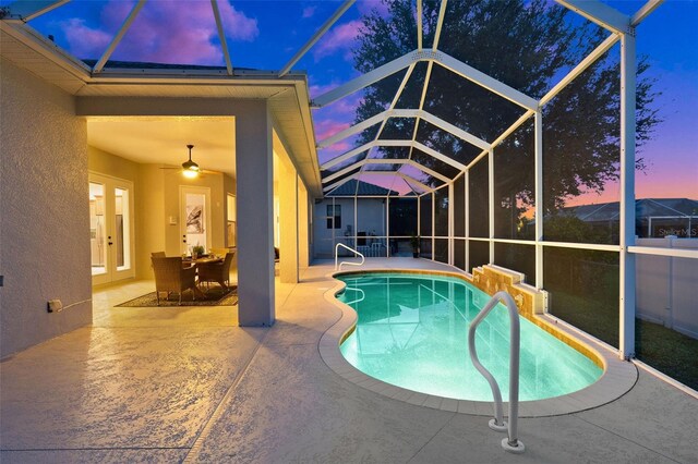 pool at dusk with ceiling fan, a lanai, and a patio area