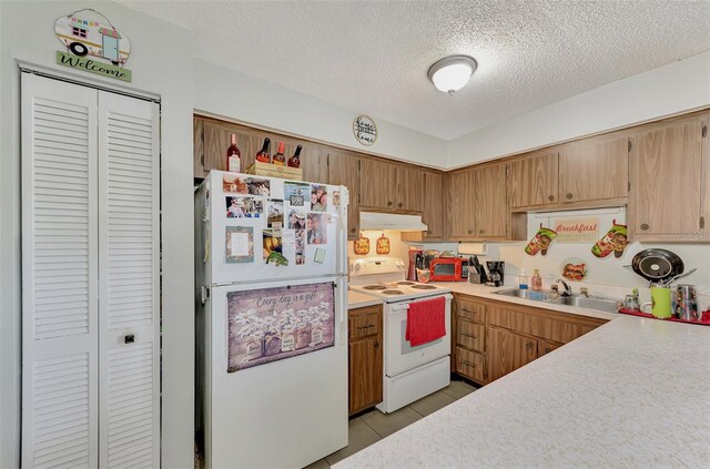 kitchen featuring white appliances, light tile patterned floors, sink, and a textured ceiling