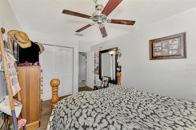 carpeted bedroom with a textured ceiling, ceiling fan, and a closet