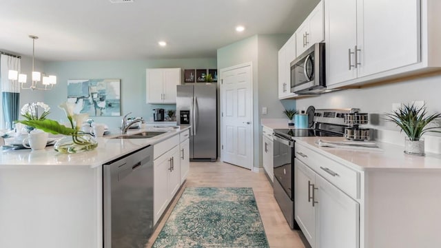 kitchen featuring sink, appliances with stainless steel finishes, light wood-type flooring, white cabinets, and pendant lighting