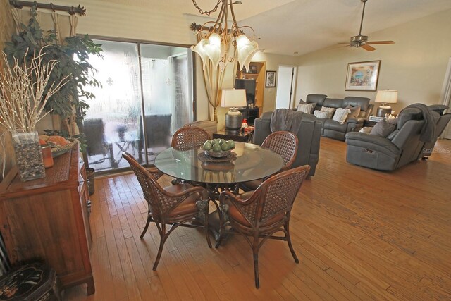 dining room with ceiling fan with notable chandelier, dark wood-type flooring, and a wealth of natural light