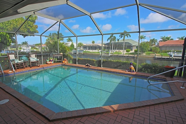 view of swimming pool featuring glass enclosure, a patio area, and a water view