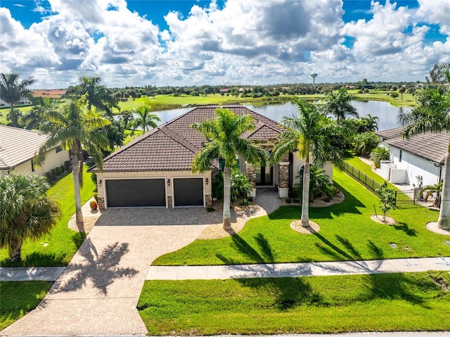 mediterranean / spanish-style home featuring a front yard, a garage, and a water view