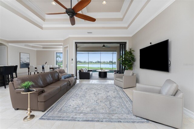 living room featuring ceiling fan, a raised ceiling, and ornamental molding