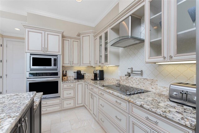 kitchen featuring light stone counters, cream cabinetry, stainless steel appliances, backsplash, and crown molding