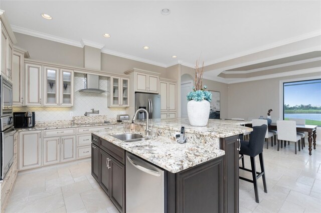 kitchen with appliances with stainless steel finishes, a large island with sink, ornamental molding, and sink