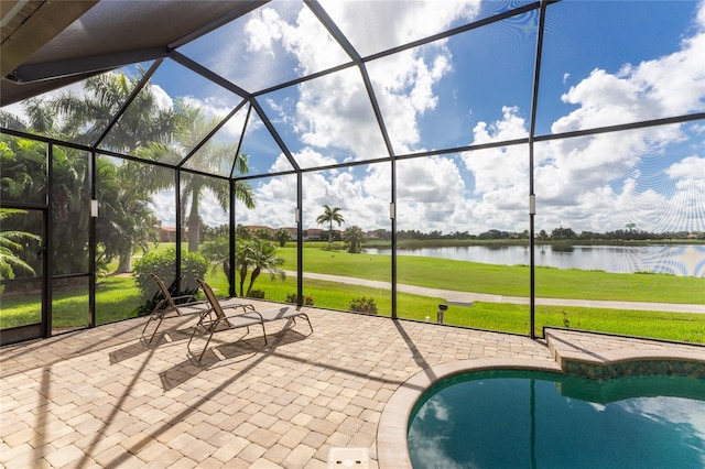 view of pool featuring glass enclosure, a water view, a yard, and a patio area