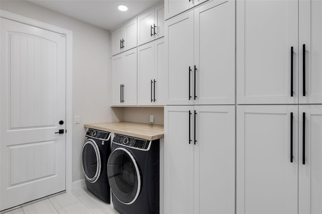 laundry area featuring light tile patterned flooring, washing machine and dryer, and cabinets