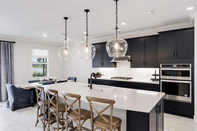 kitchen with a breakfast bar area, sink, a kitchen island with sink, and stainless steel appliances