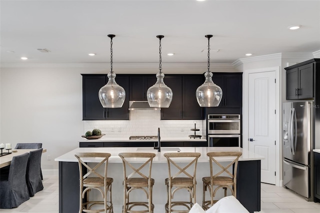 kitchen featuring hanging light fixtures, backsplash, a center island with sink, sink, and appliances with stainless steel finishes