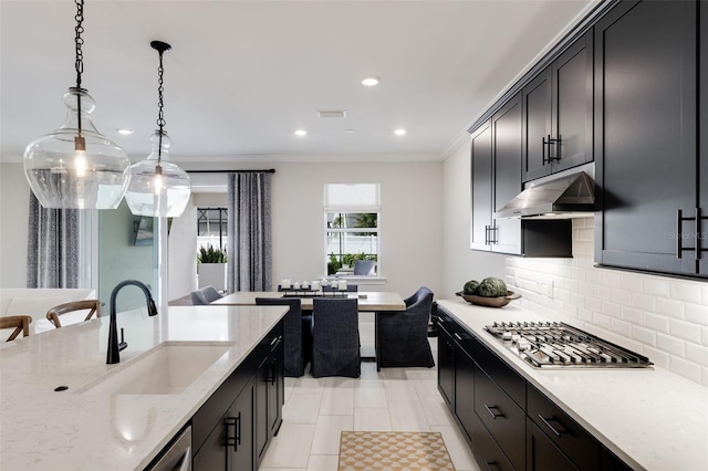 kitchen with decorative backsplash, hanging light fixtures, light stone counters, stainless steel gas cooktop, and sink