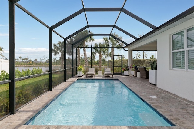 view of swimming pool with a patio, a water view, and glass enclosure