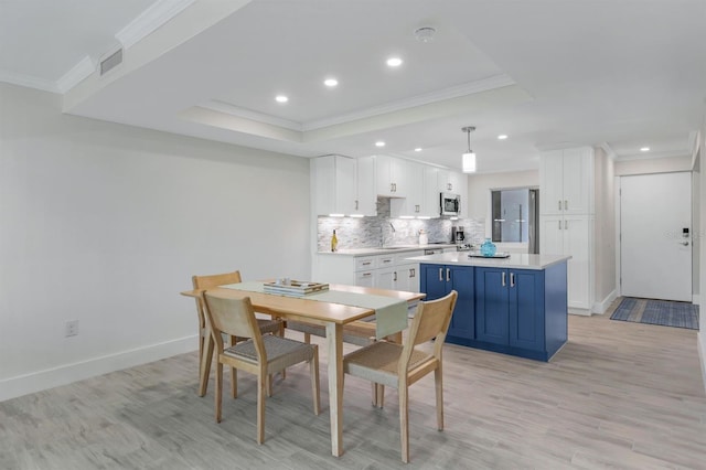 dining area with light wood-type flooring, a raised ceiling, and ornamental molding