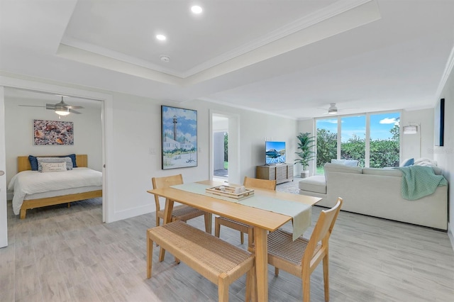 dining room with crown molding, light hardwood / wood-style flooring, ceiling fan, and a tray ceiling