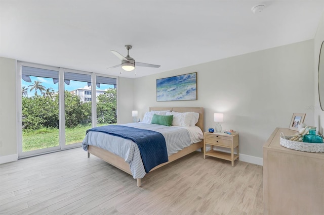 bedroom with access to exterior, ceiling fan, a wall of windows, and light hardwood / wood-style floors