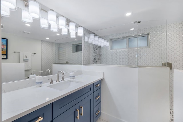 bathroom with a tile shower and vanity