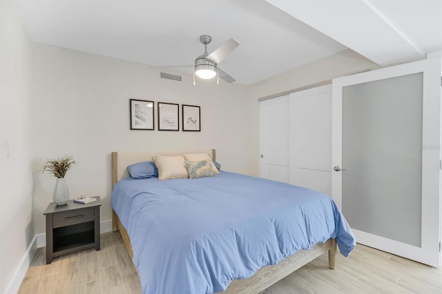 bedroom with light wood-type flooring, ceiling fan, and a closet