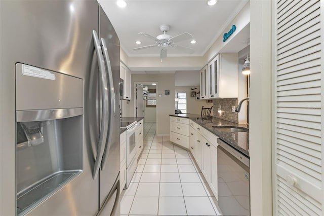 kitchen featuring white cabinets, backsplash, stainless steel appliances, sink, and ceiling fan