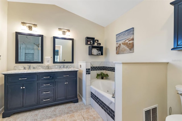 bathroom with tile patterned floors, vaulted ceiling, a relaxing tiled tub, and vanity