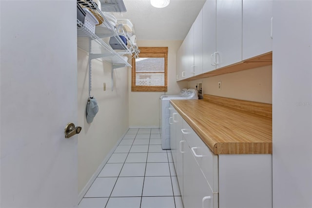 washroom featuring hookup for a washing machine, cabinets, and light tile patterned floors