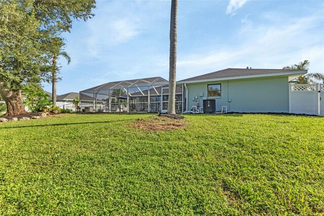 rear view of property with a lawn, a lanai, and central AC unit