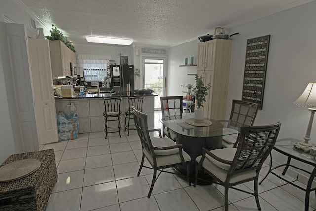 tiled dining space with ornamental molding, sink, and a textured ceiling