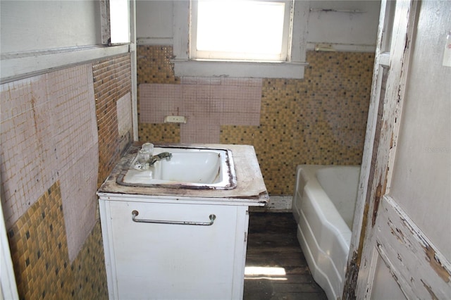 bathroom with a bath, decorative backsplash, vanity, and hardwood / wood-style floors