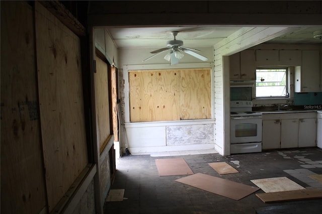 kitchen with wooden walls, electric stove, and ceiling fan