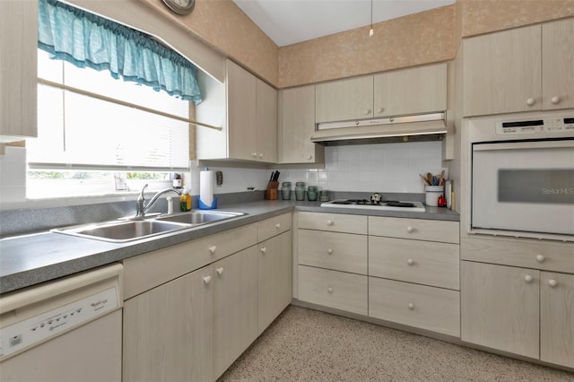 kitchen featuring backsplash, white appliances, and sink