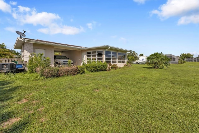 rear view of property with a lawn and a carport