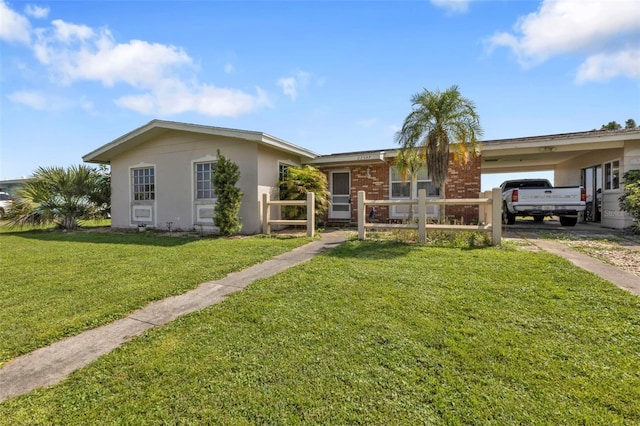 ranch-style home featuring a carport and a front lawn