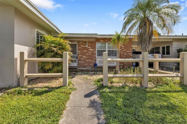 view of side of home featuring brick siding, stucco siding, and fence