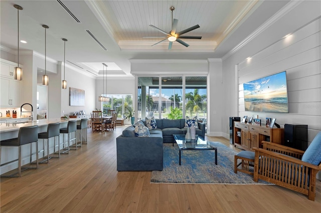 living room with crown molding, a raised ceiling, ceiling fan, and hardwood / wood-style floors